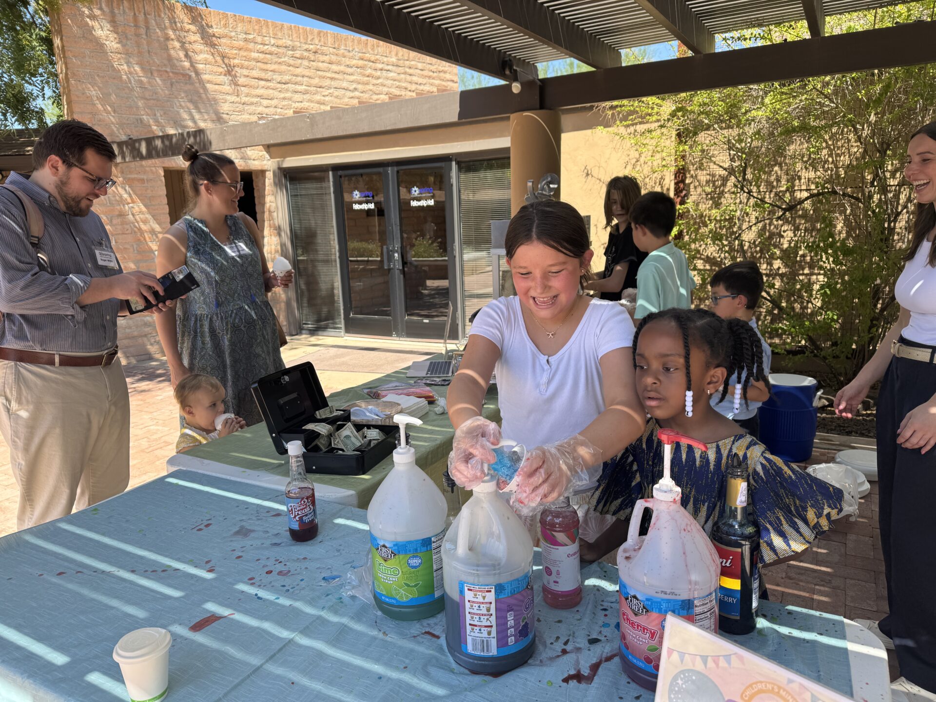 BeTween snow cone stand with kids serving and volunteers nearby