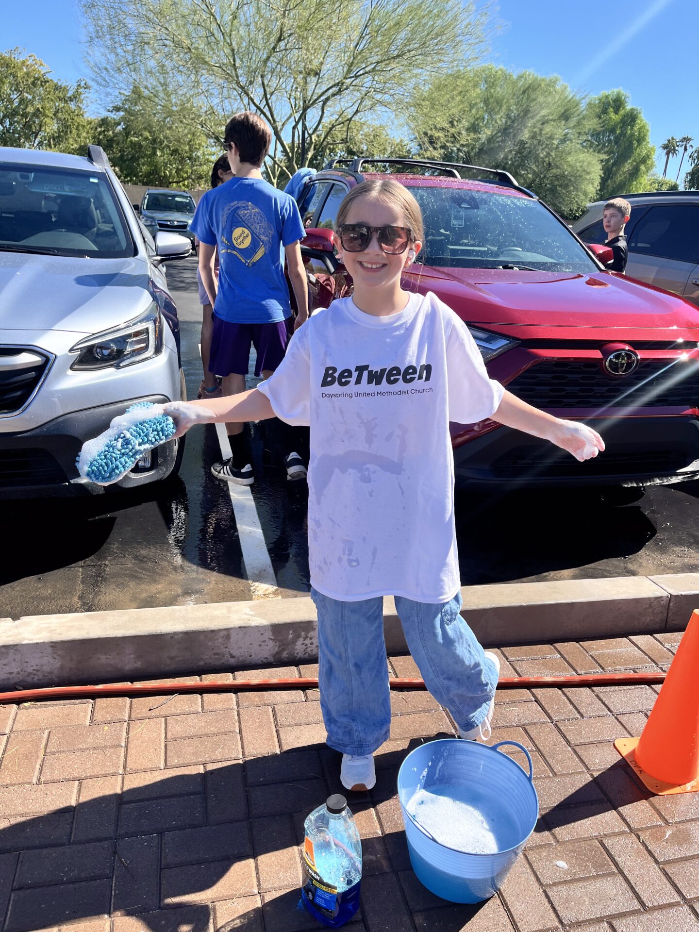 BeTween car wash fundraiser with a child holding a sponge and bucket