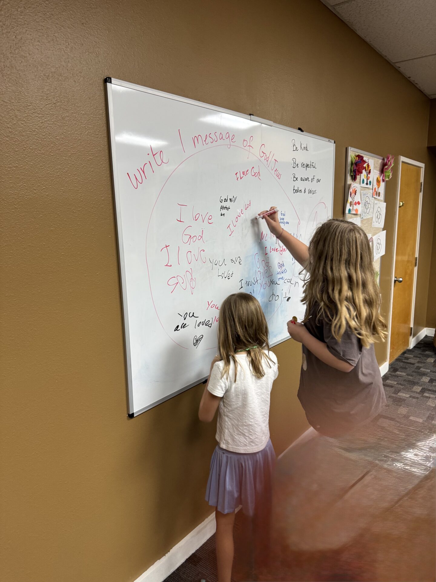 Kids writing messages of love and kindness on a whiteboard